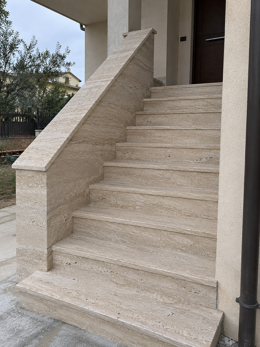 Scala esterna in travertino con gradini, alzate e parapetto rivestito